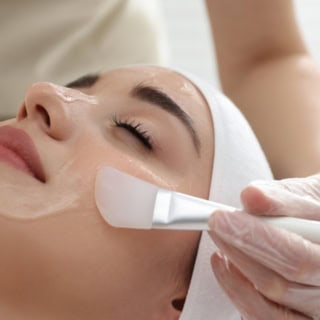 Mit einem Pinsel wird die Fruchtsäure im Gesicht verteilt.