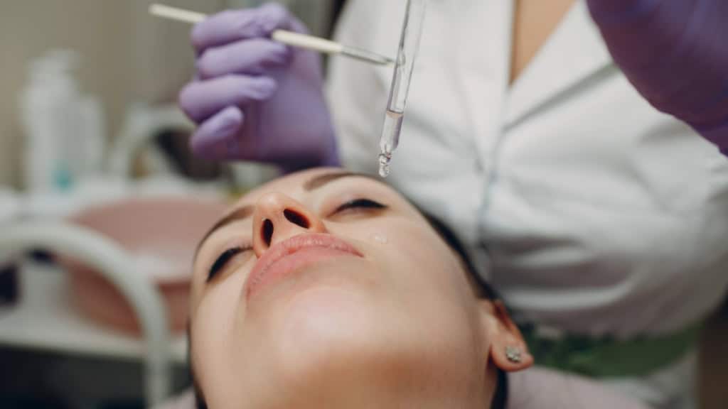 Fruchtsäure Peeling-Gesicht Bei einer Fruchtsäure Behandlung wird einer Frau Fruchtsäure mit einer Pipette verabreicht.