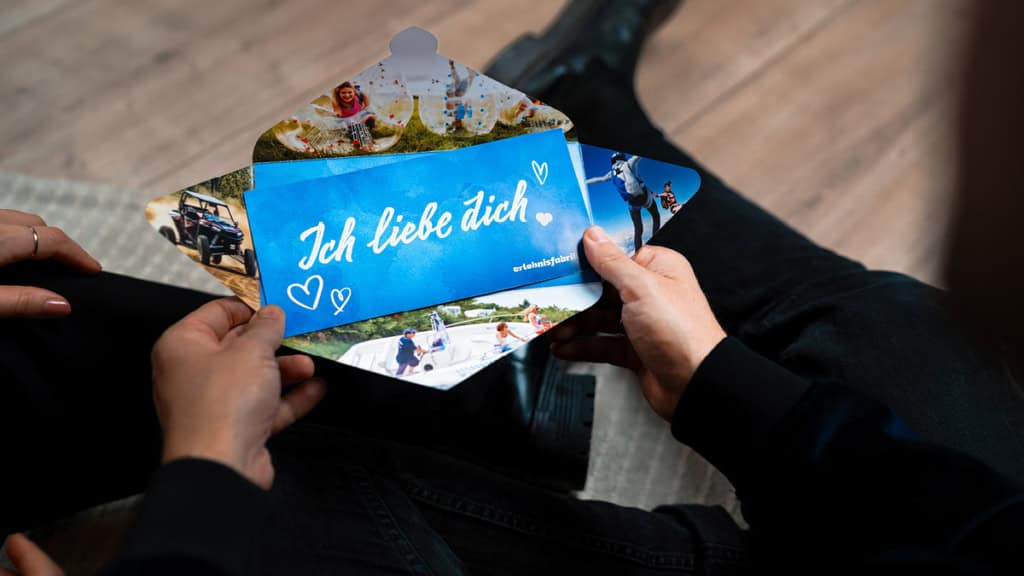 Geschenkbox - Weihnachten - gutschein - oeffnen Ein geöffneter Umschlag in dem ein Erlebnisgutschein ist auf dem ich liebe dich steht.