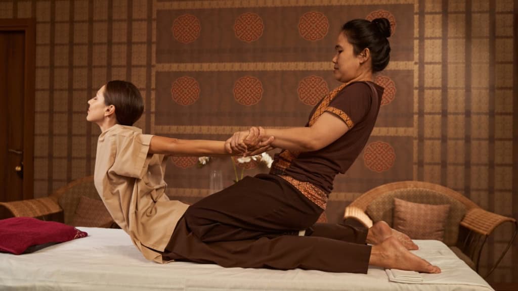 Thai Ganzkörpermassage-Druckbewegung Mit Dehnbewegungen werden bei einer Frau Verspannungen gelöst - Thai Ganzkörpermassage.