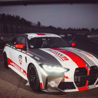 BMW M4 vor der Rennstrecke mit eingeschalteten Licht