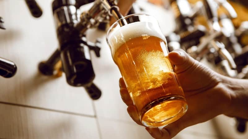 Ein Bier wird in einer Bar frisch aus einem Bierfass in ein Bierglas gezapft.