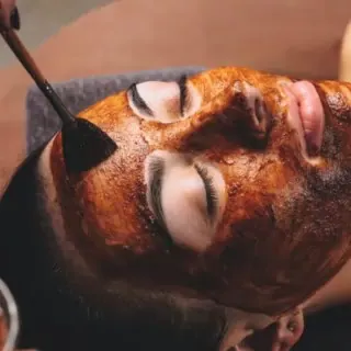 Frau auf einer Behandlungsliege bei der Bio Microneedling Behandlung mit Gesichtsmaske.