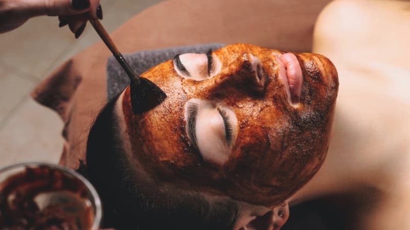 Frau auf einer Behandlungsliege bei der Bio Microneedling Behandlung mit Gesichtsmaske.