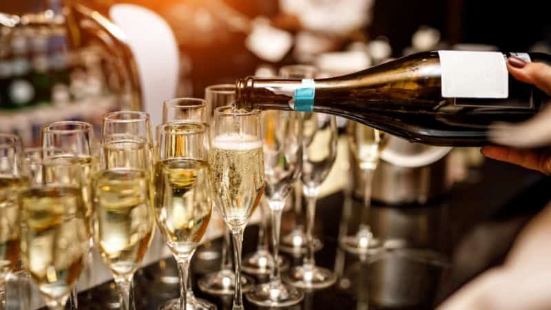 Eine Barkeeperin schenkt Champagner aus einer Champagnerflasche in Sektgläser für eine Champagner Verkostung ein.