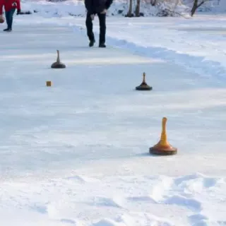 Eine Gruppe spielt Eisstockschießen auf einer Eisbahn in Dresden.