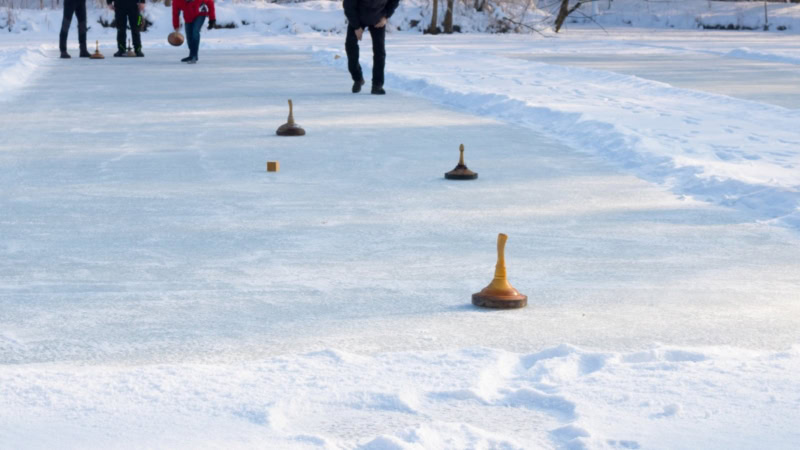 Eine Gruppe spielt Eisstockschießen auf einer Eisbahn in Dresden.