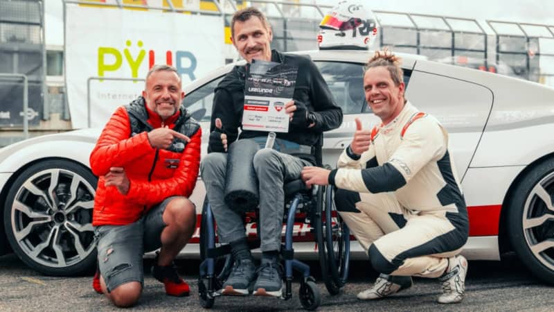 Handicap Fahrer mit Instruktoren vor einen Traumwagen bei der Urkundenübergabe