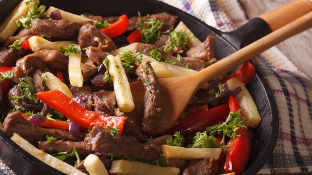 Peruanischer Kochkurs-Lomo Saltado In der Pfanne wird Kartoffel und Rindfleisch gewendet für ein peruanisches Gericht Lomo Saltado.