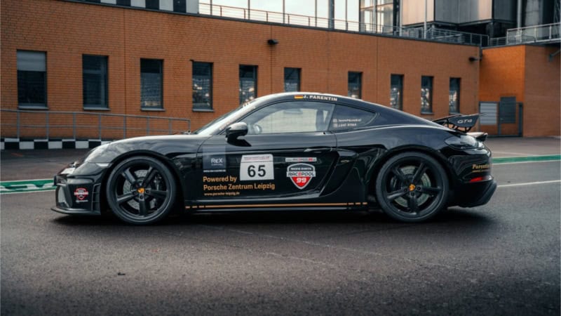 Porsche 718 GT4 in seitlicher Ansicht vor einem Gebäude bei der Rennstrecke.