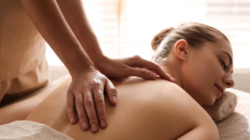 Eine Frau bei der Rückenmassage auf einer Massageliege.