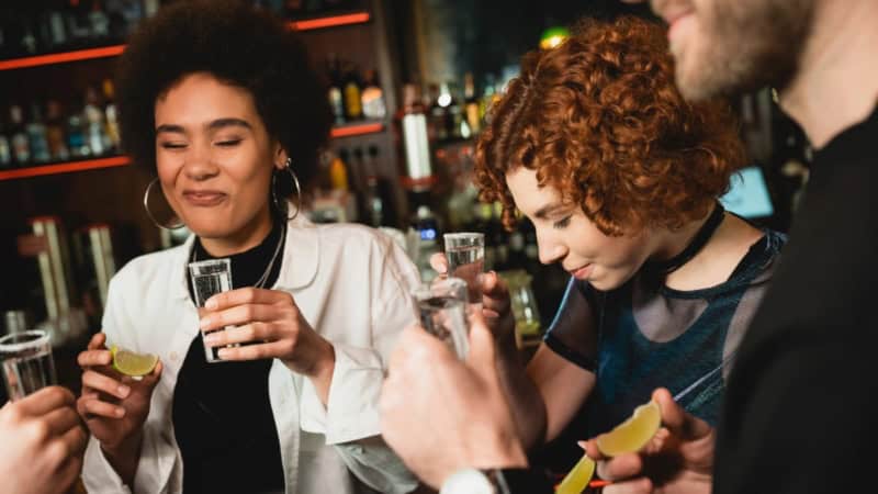 Gruppe von vier Personen verkostet gemeinsam Tequila aus kleinen Gläsern in einer Bar.