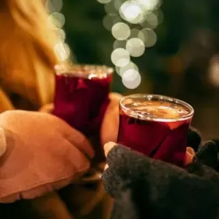Nahaufnahme eines Paares, das frischen Glühwein in Gläsern in der Hand hält