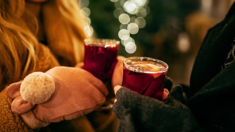 Nahaufnahme eines Paares, das frischen Glühwein in Gläsern in der Hand hält