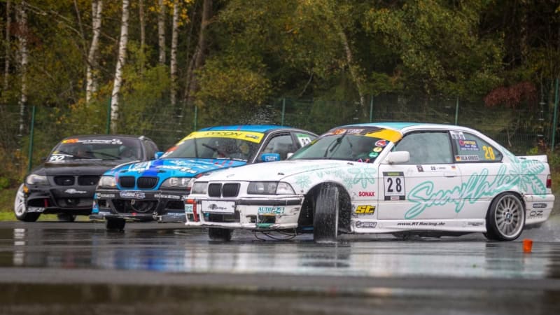 Drei Sportautos driften auf nassem Asphalt am Nürburgring.