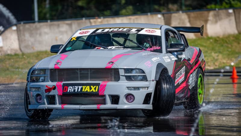 Graues Sportauto driftet über eine nasse Straße am Nürburgring.