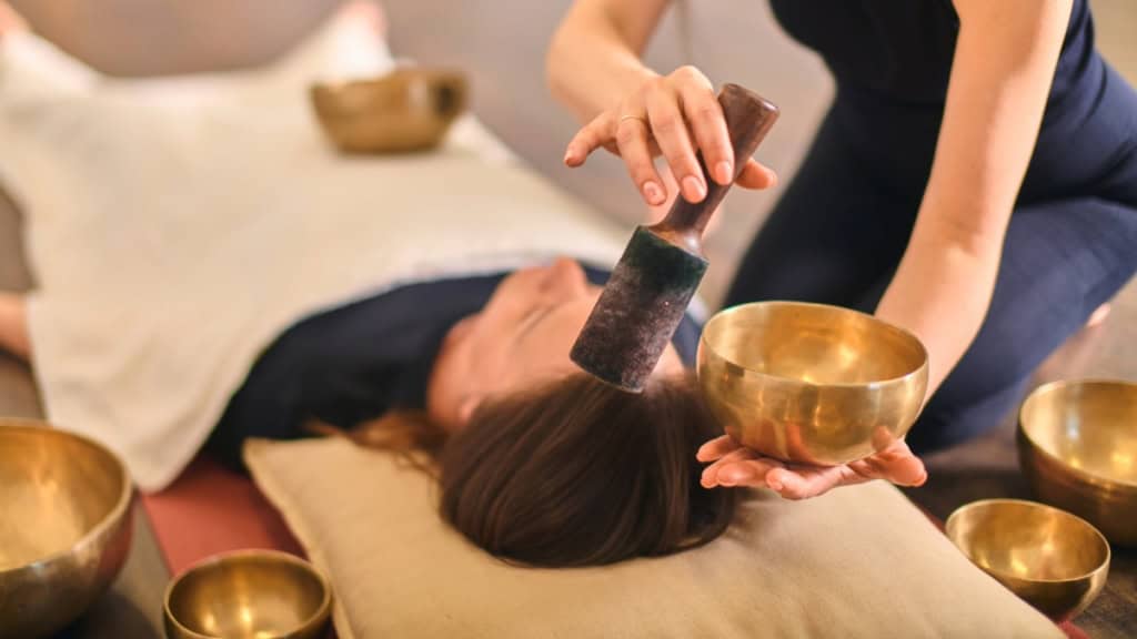 Eine Frau wird mit einer Klangschale Energie behandelt.