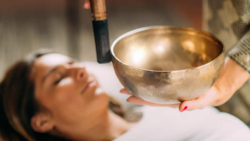 Ein Frau die mit einer Klangschale behandelt wird.