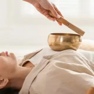 Eine Frau die mit einer Klangschale auf ihrer Brust behandelt wird.