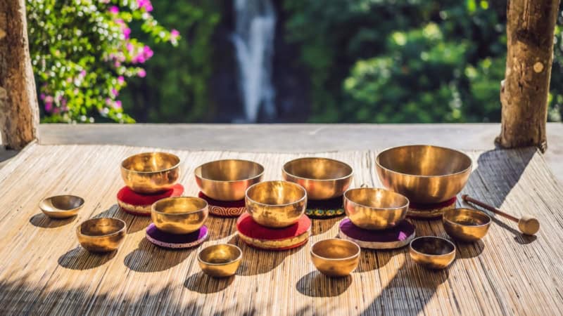 Viele verschiedene Klangschalen die auf einer Bambus Matte zusammen stehen.