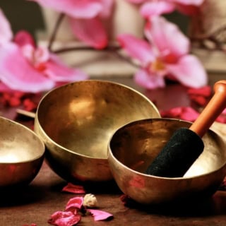 3 Klangschalen die zwischen Blumen liegen.