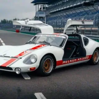 Der Melkus RS 1000 mit offenen Flügeltüren auf einer Rennstrecke.