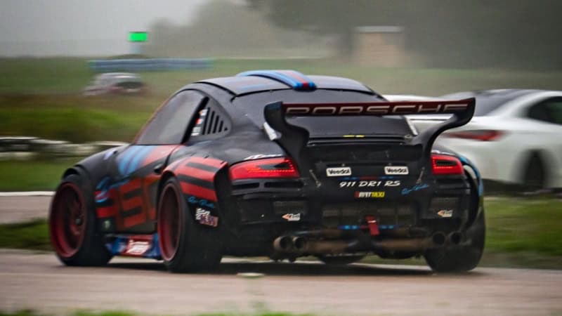 Rückansicht eines Porsche Sportwagens der mit hoher Geschwindigkeit über eine Rennstrecke fährt.