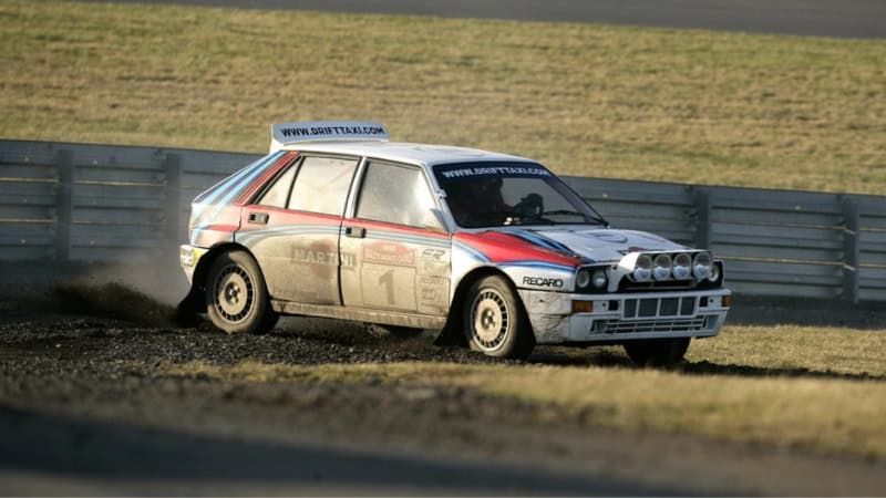 Ein Sportauto fährt über den Rasen einer Rennstrecke.