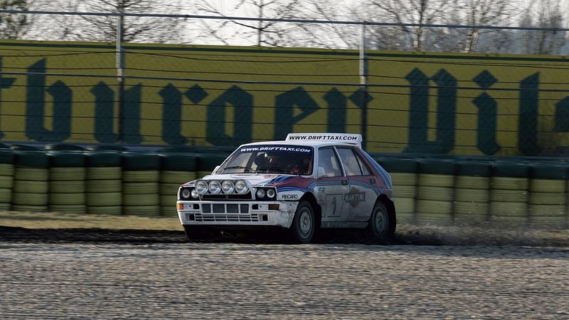 Ein Sportauto fährt mit hoher Geschwindigkeit über einen Schotterboden auf einer Rennstrecke.