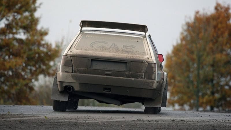 Rückansicht eines dreckigen Autos auf einer Straße im Wald.