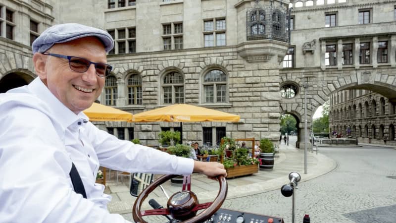 Guide auf einer e-Kutsche in den Straßen von Leipzig, auf einer Rundfahrt vor einem Historischen Gebäude.