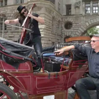 Bei der Musiktour mit einer elektrischen Kutsche in Leipzig spielt ein Musiker auf der Kutsche klassische Musik.