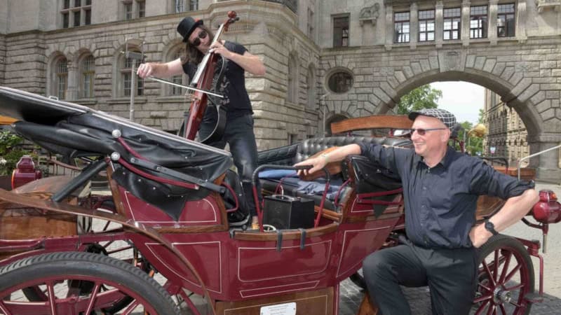 Bei der Musiktour mit einer elektrischen Kutsche in Leipzig spielt ein Musiker auf der Kutsche klassische Musik.