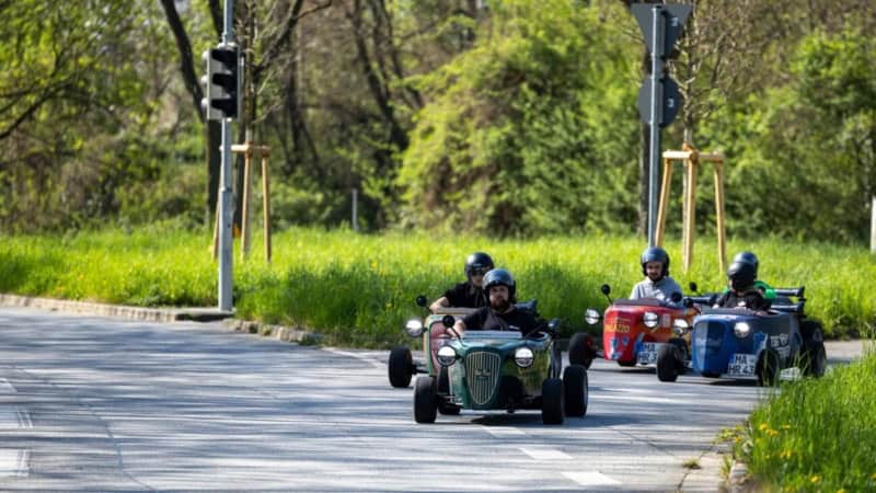 Eine Gruppe Hotrod Fahrer die bei einer Hotrod Tour gemeinsam in eine andere Straße einlenken.
