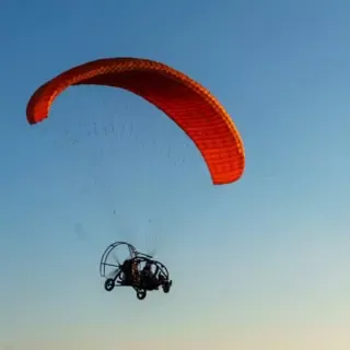 Ansicht auf einen fliegenden, motorisierten, Gleitschirmflieger von unten.
