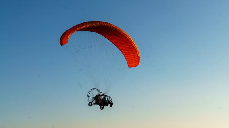 Ansicht auf einen fliegenden, motorisierten, Gleitschirmflieger von unten.