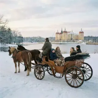 winter-familie Erlebnisse für die Familie. Eine Familie fährt in einer Pferdekutsche durch das verschneite Moritzburg.