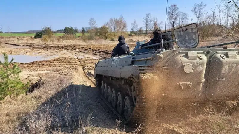 Ein Panzer von hinten der durch Matsch fährt. Der Matsch spritzt hinter dem Panzer hoch.