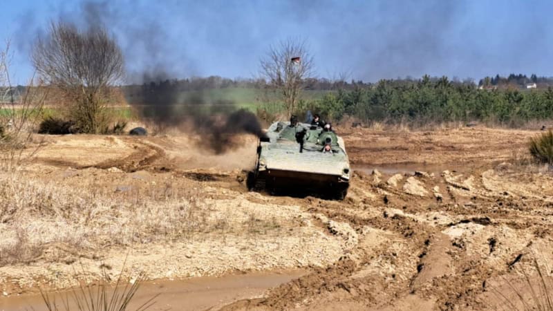 Ein Panzer der durch Matsch fährt und eine große Rauchwolke ausstößt.