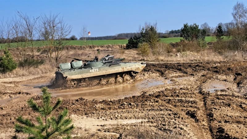 Ein Panzer der durch Schlamm fährt und mitten in einer Pfütze steht.