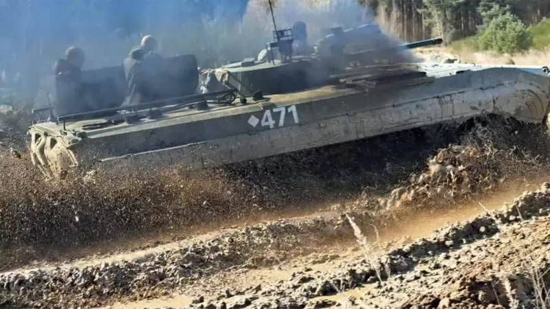 Ein Panzer der schnell durch eine Pfütze fährt und das Wasser hoch spritzen lässt.