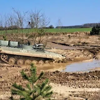 Ein Panzer der auf eine Pfütze zufährt.