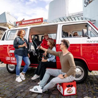 Ein Vw Bulli der vor dem Schokoladenmuseum in Köln parkt. Die Bulli Tour Teilnehmer stoßen gemeinsam auf ein kölsch an.