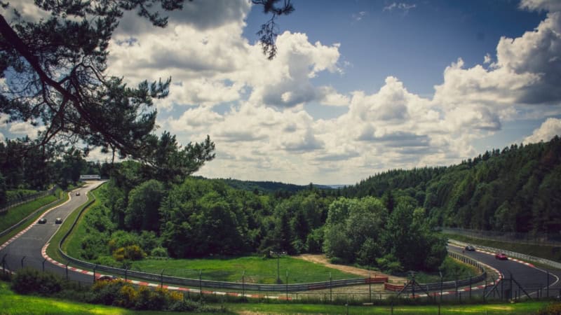 Eine befahrene Kurve auf dem Nürburgring. Eine Naturkulisse mit kurviger Straße, umgeben von Wäldern.