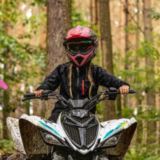 Mädchen fährt auf Quad durch den Wald