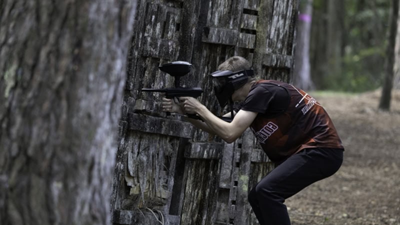 Paintballspieler versteckt sich hinter einer hölzernen Deckung
