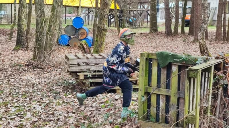Paintballspieler mit Markierer in der Hand wechselt die Deckung