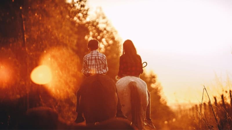 Ein Junge und ein Mädchen reiten gemeinsam im im Sonnenuntergang - Pferde Erlebnis im Osterzgebirge.