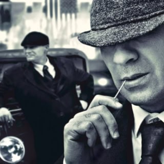 Zwei Männer im Stil der 1920er Jahre vor einem Oldtimer in schwarz weiß - Stadtführung in Berlin.