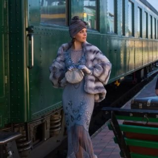 Elegant gekleidete Frau im Stil der 1920er Jahre steigt in historischen Zug ein.